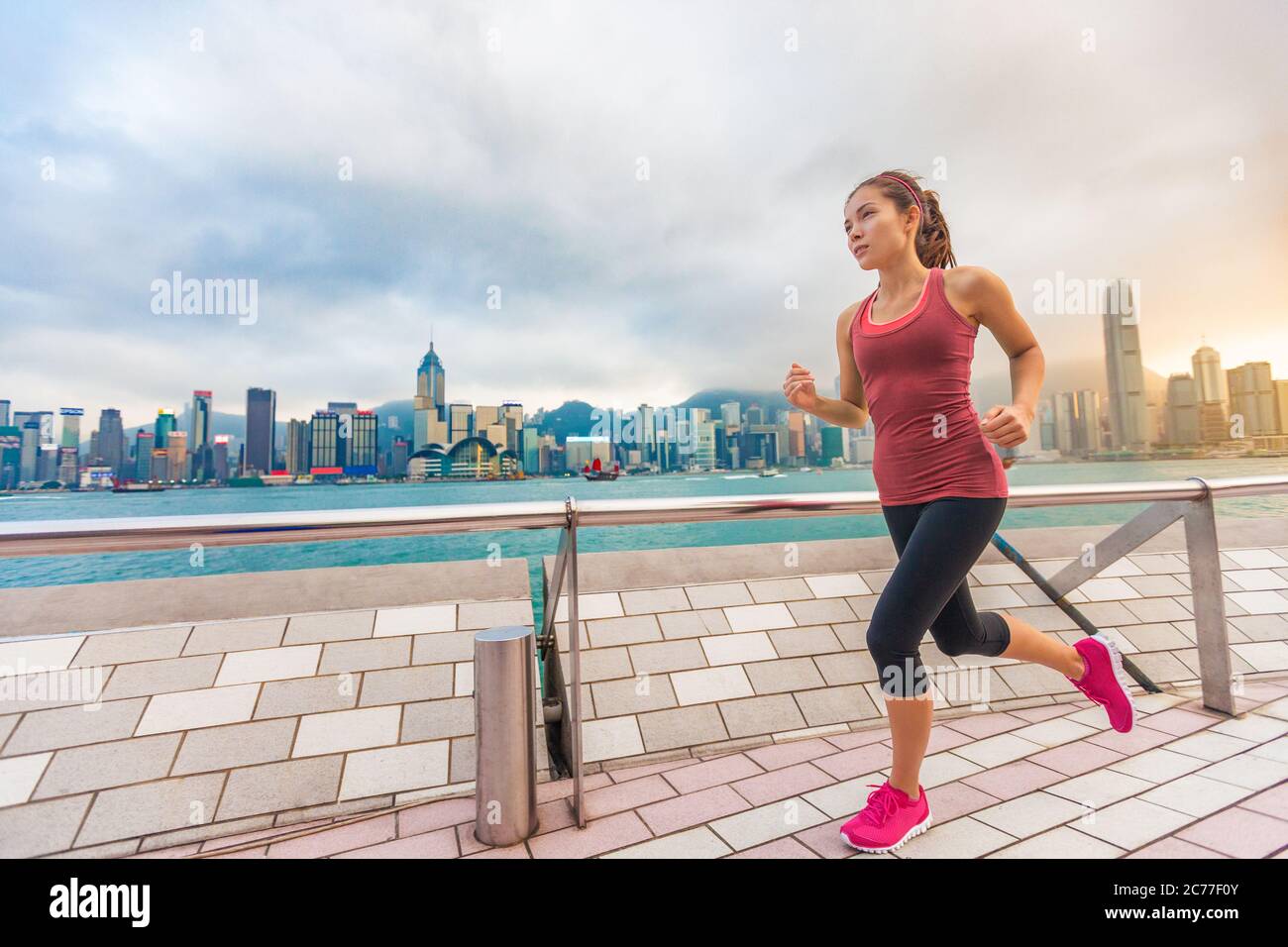 Stadt laufen - Frau runner und die Skyline von Hongkong. Weibliche Athleten fitness Sportler joggen training Leben gesunder Lebensstil auf Tsim Sha Tsui Promenade Stockfoto