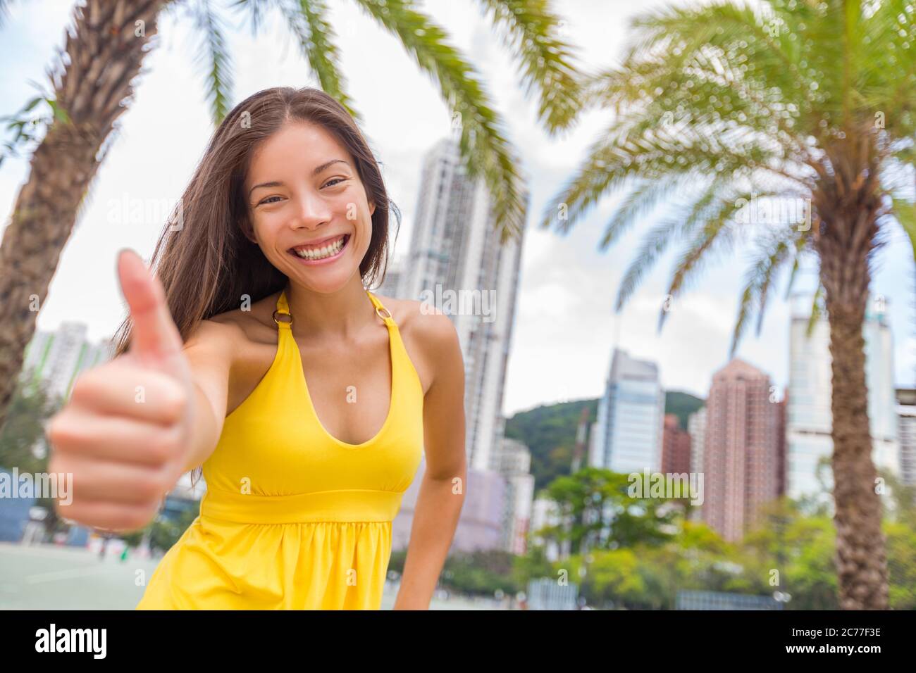 Happy chinese girl doing Daumen nach oben in Zufriedenheit in Hong Kong Stadt, Asien China Reise Lebensstil. Junge lächelnde multirassische Frau Stockfoto