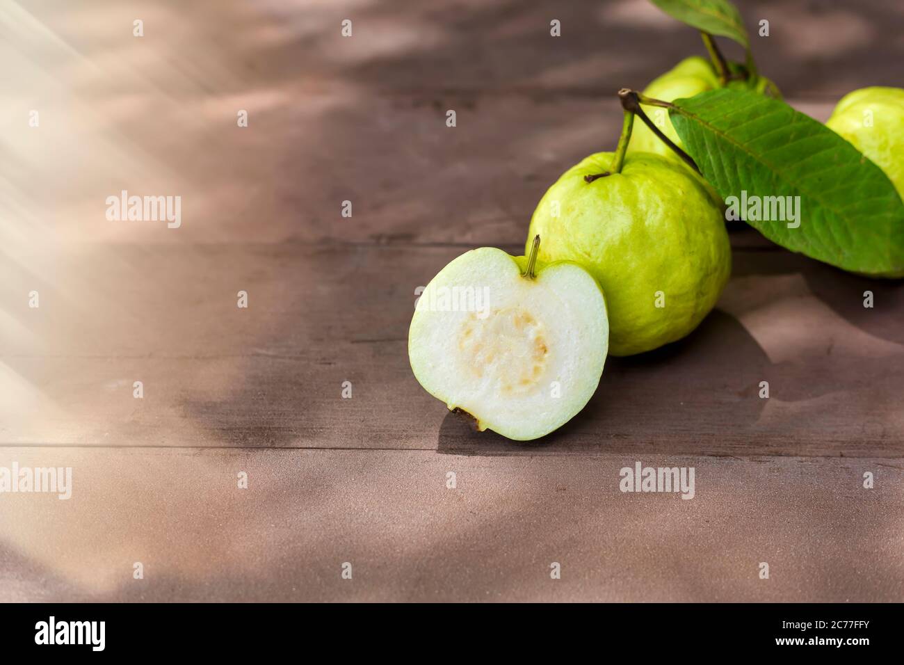 Frisches Guava Obst auf Holztisch mit Sonnenstrahl. Frische Guava-Rutsche. Stockfoto