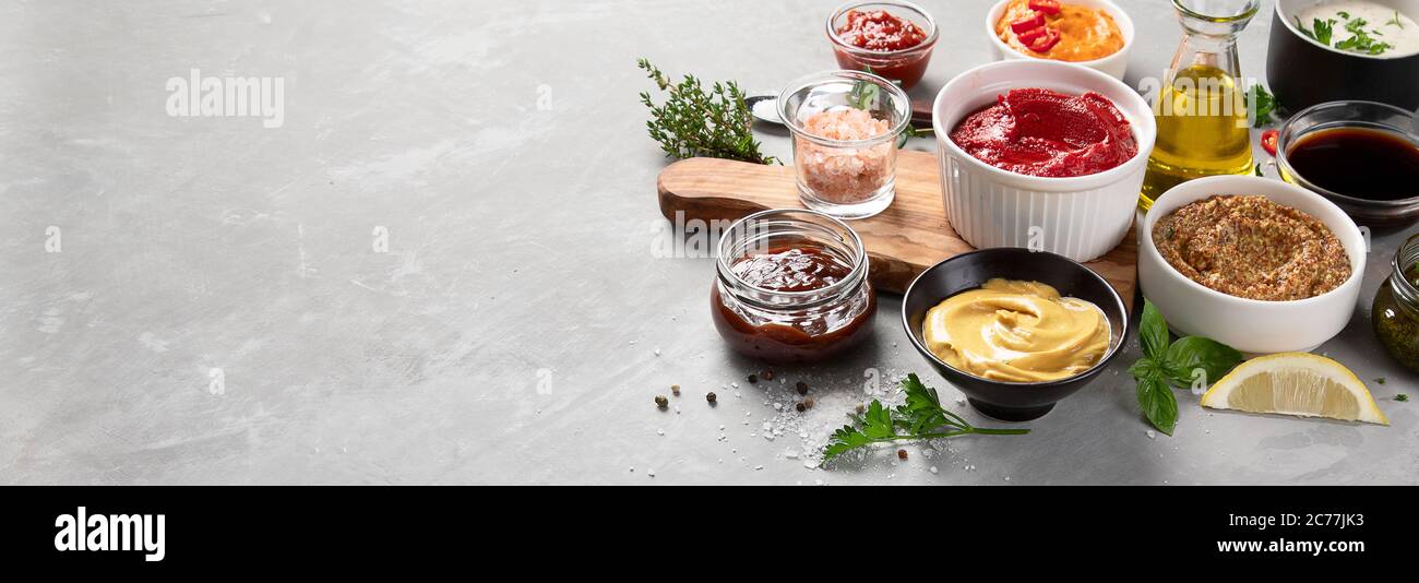 Set aus verschiedenen Saucen in Schalen auf grauem Hintergrund. Panorama, Banner mit Kopierplatz Stockfoto