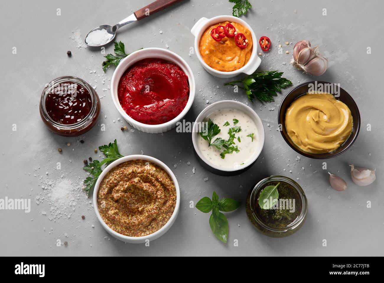 Set aus verschiedenen Saucen in Schalen auf grauem Hintergrund. Draufsicht Stockfoto