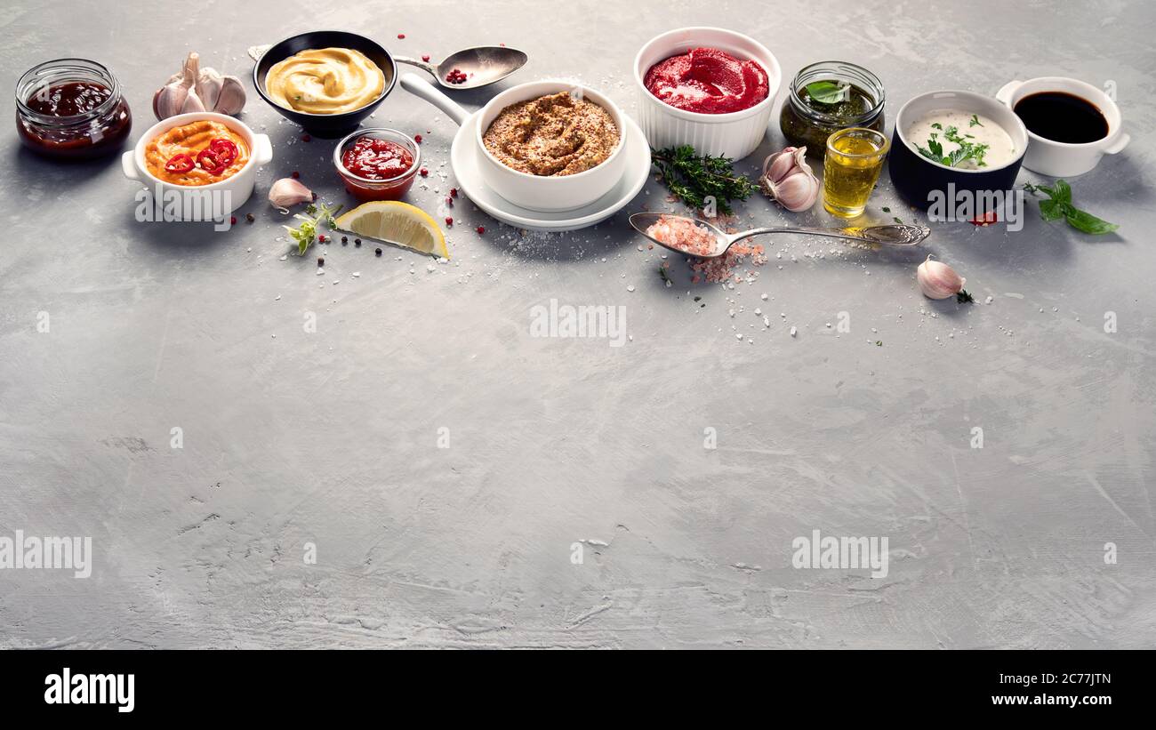 Set aus verschiedenen Saucen in Schalen auf grauem Hintergrund. Bild mit Kopierbereich Stockfoto