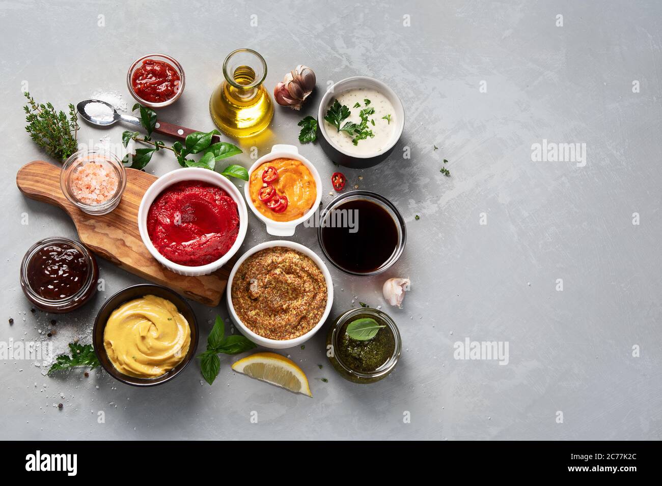 Set aus verschiedenen Saucen in Schalen auf grauem Hintergrund. Draufsicht mit Kopierbereich Stockfoto