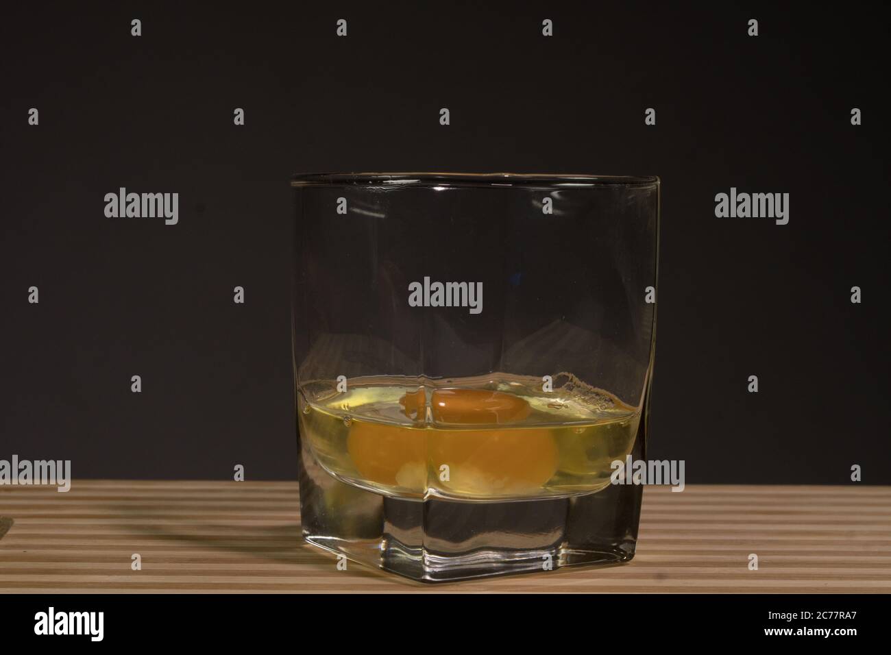 Rohes Ei in einem Glasbecher. Auf schwarzem Hintergrund Stockfoto