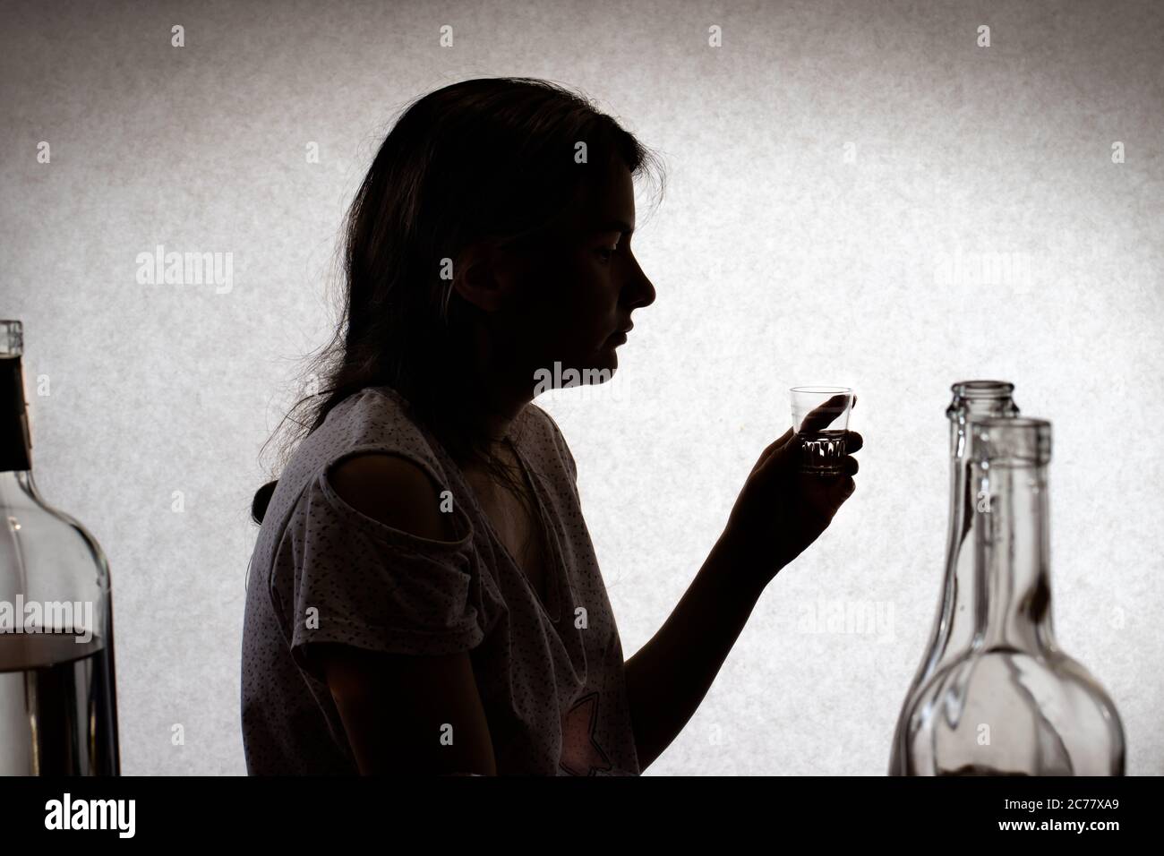 Frau hält ein Glas mit starkem Alkohol. Weiblicher Alkoholismus, Alkoholabhängigkeit, Delirium tremens. Silhouette Foto. Stockfoto