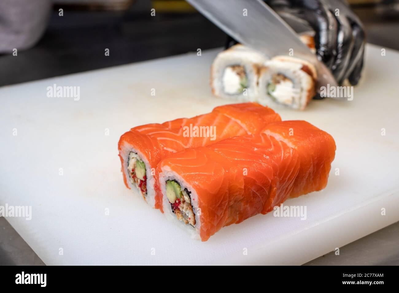 Das Sushi in Stücke schneiden. Brötchen, Kochen. Japanische Küche. Stockfoto