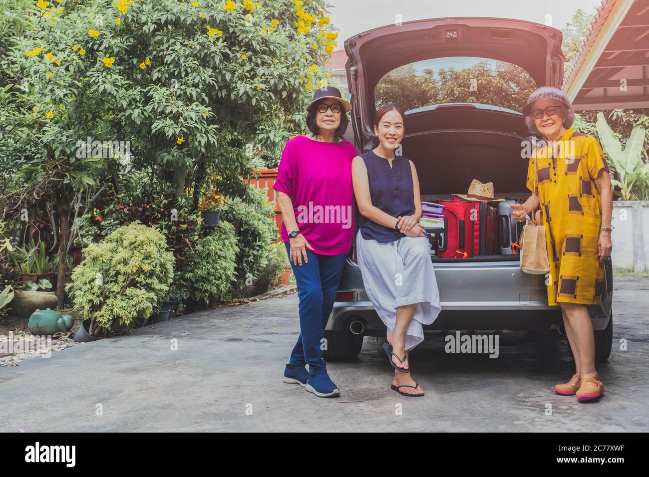 Zwei ältere Frauen und eine Erwachsene Frau mit Koffern auf Autotour. Stockfoto