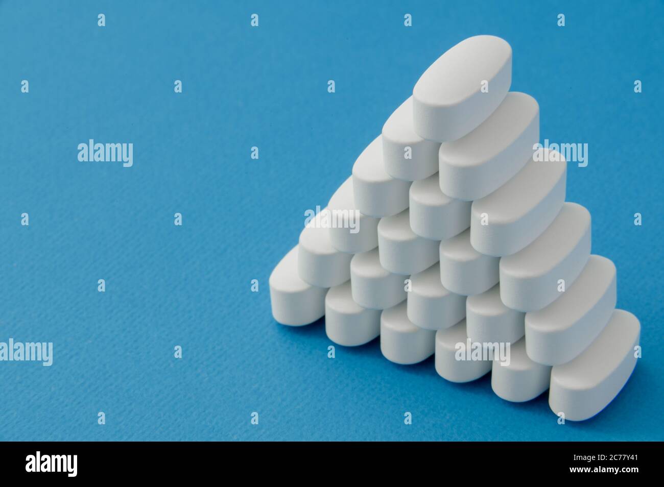 Pyramide aus weißen Vitamin-Medikamenten Medikationstabletten auf blauer reiner Oberfläche mit Kopierraum Stockfoto