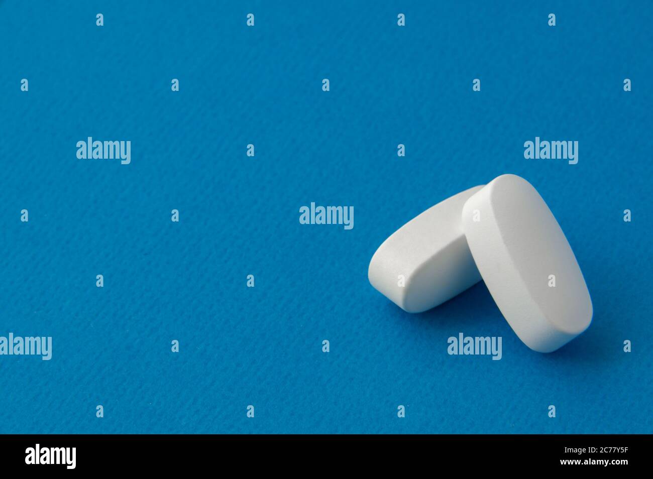 Zwei weiße Tabletten auf blauer Oberfläche Stockfoto