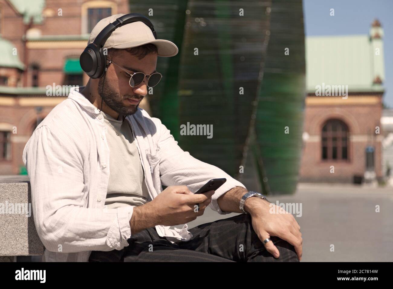 Umea, Norrland Schweden - 19. Juni 2020: Junger Mann sitzt und schaut auf sein Handy Stockfoto
