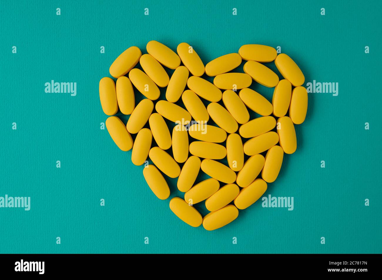 Cardio Health Care Konzept der gelben Pillen Tabletten in Herzform auf blauer Oberfläche mit Kopieplatz Stockfoto