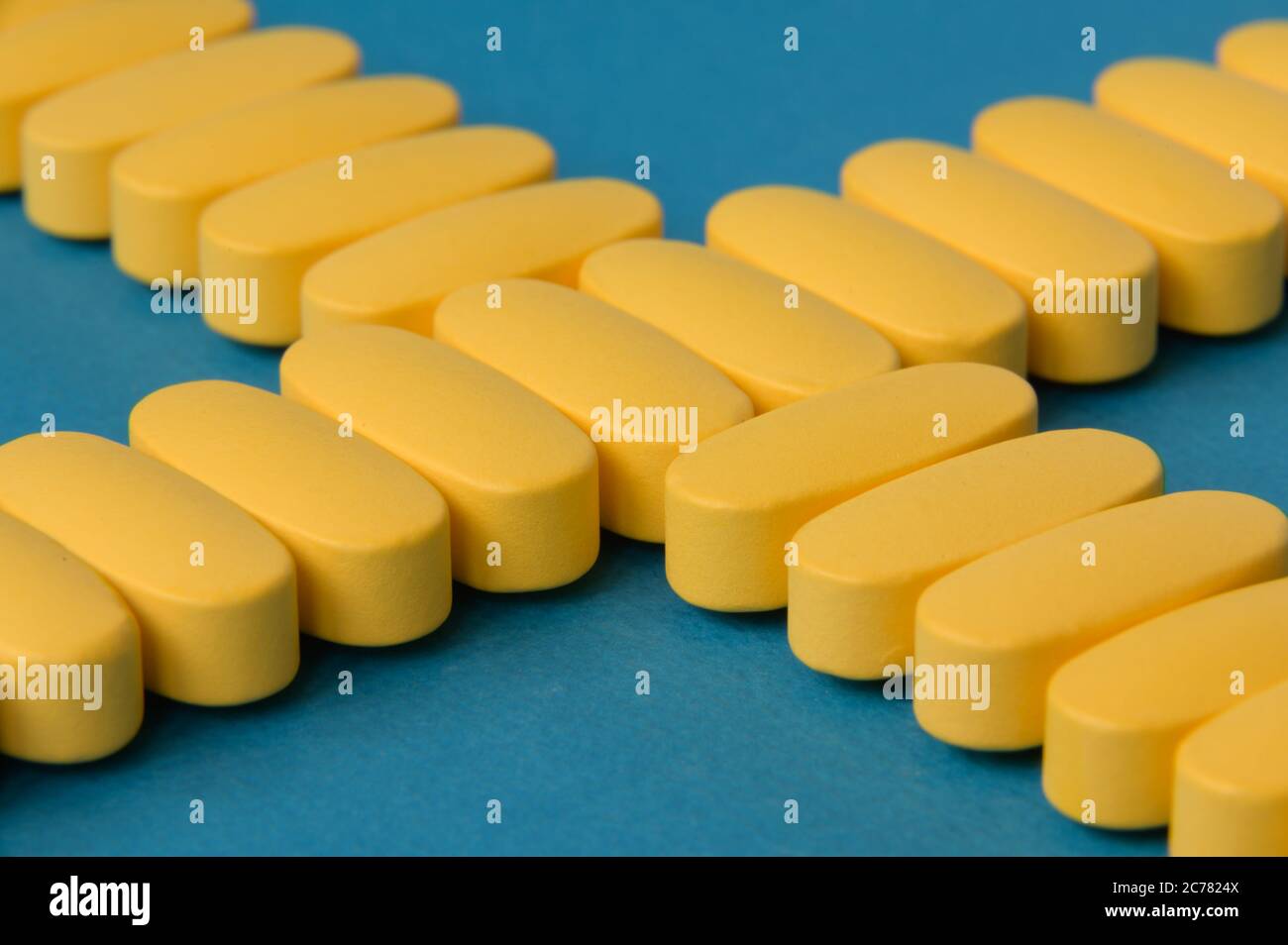 Healthcare Medizin Konzept der gelben Pillen Tabletten auf blauer Oberfläche Stockfoto
