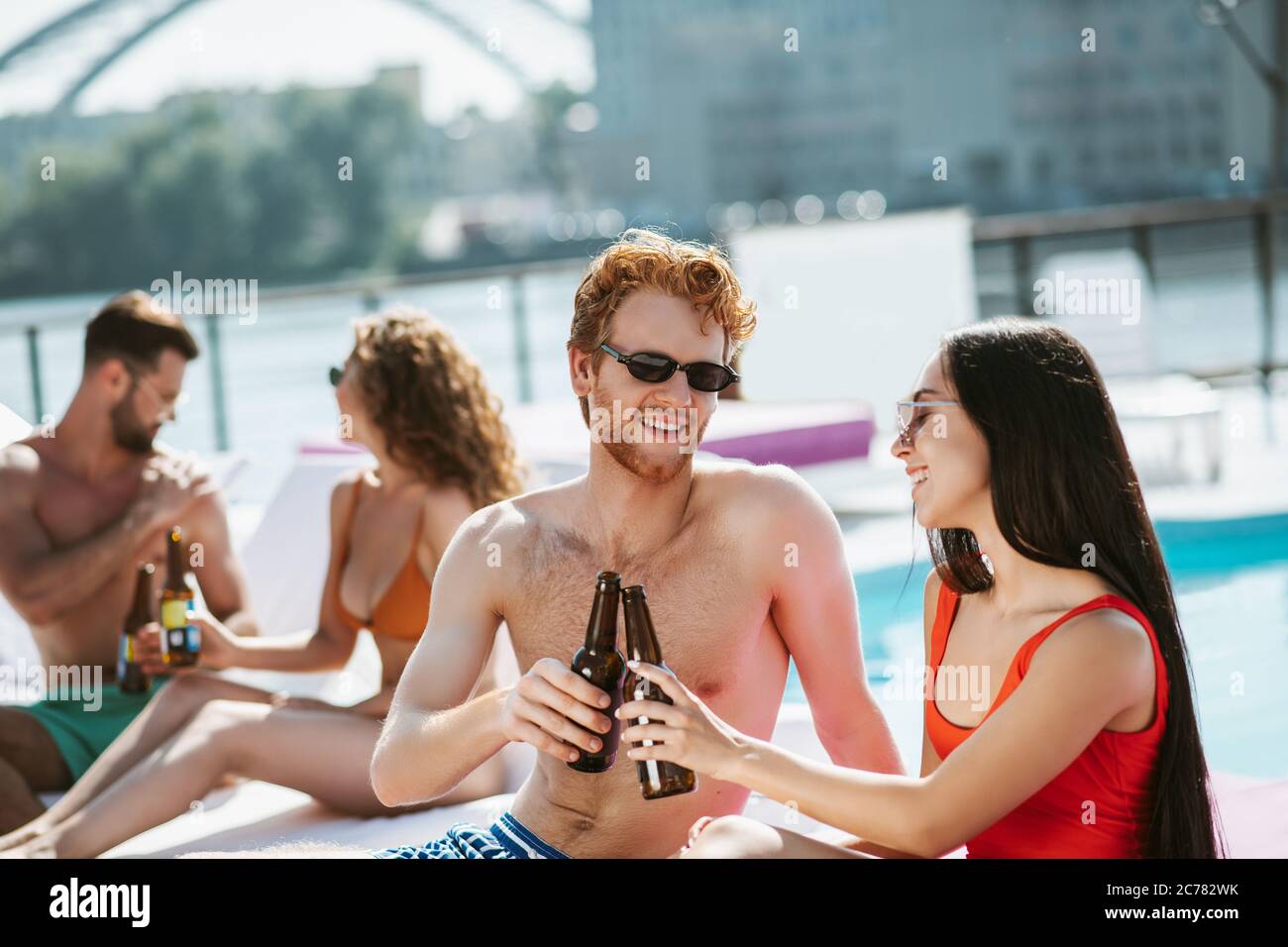 Junge Männer und Frauen trinken zusammen Bier und fühlen sich kokett Stockfoto