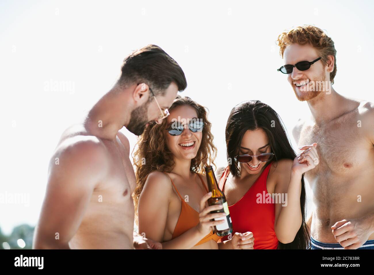 Junge Leute in Badeanzügen haben gute Zeit Bier trinken, kokett fühlen Stockfoto