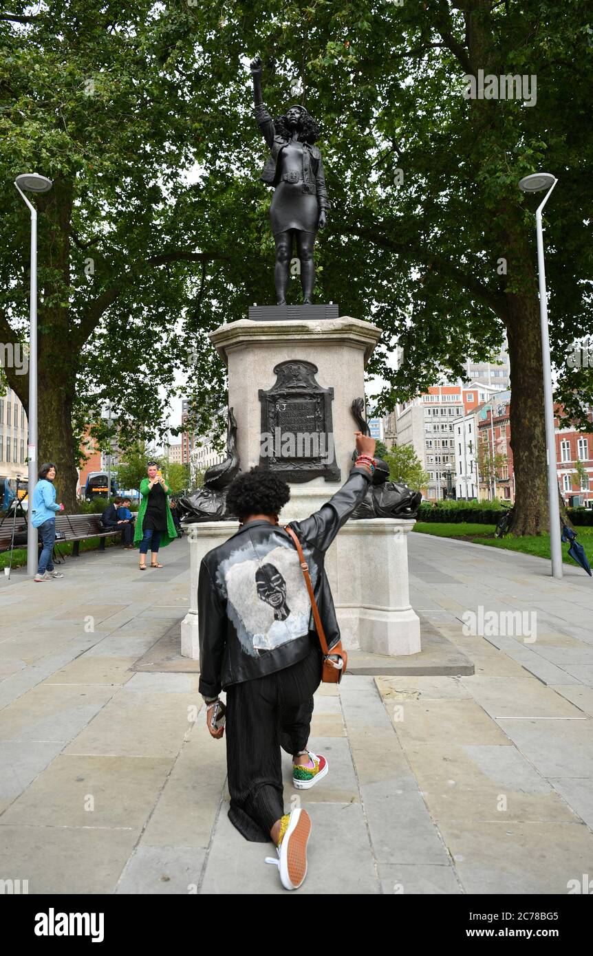 Eine Frau gibt einen Black Power Salute, während sie ein Knie vor EINER Woge der Macht (jen Reid) 2020, von prominenten britischen Bildhauer Marc Quinn, die in Bristol auf dem Gelände der gefallenen Statue des Sklavenhändlers Edward Colston installiert wurde. Stockfoto