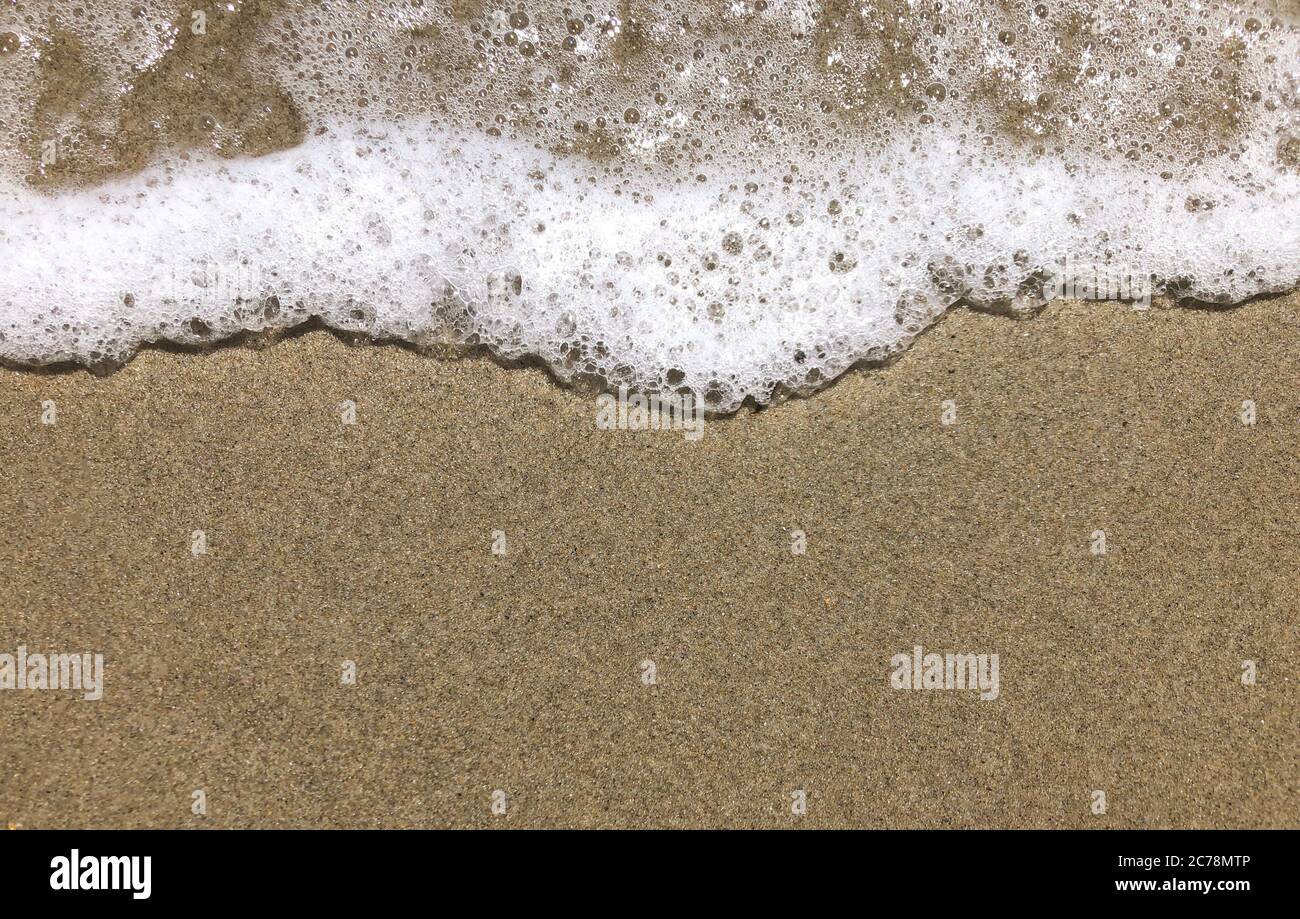 Nahaufnahme einer kleinen glatten Welle am Strand am Abend als Hintergrund Stockfoto