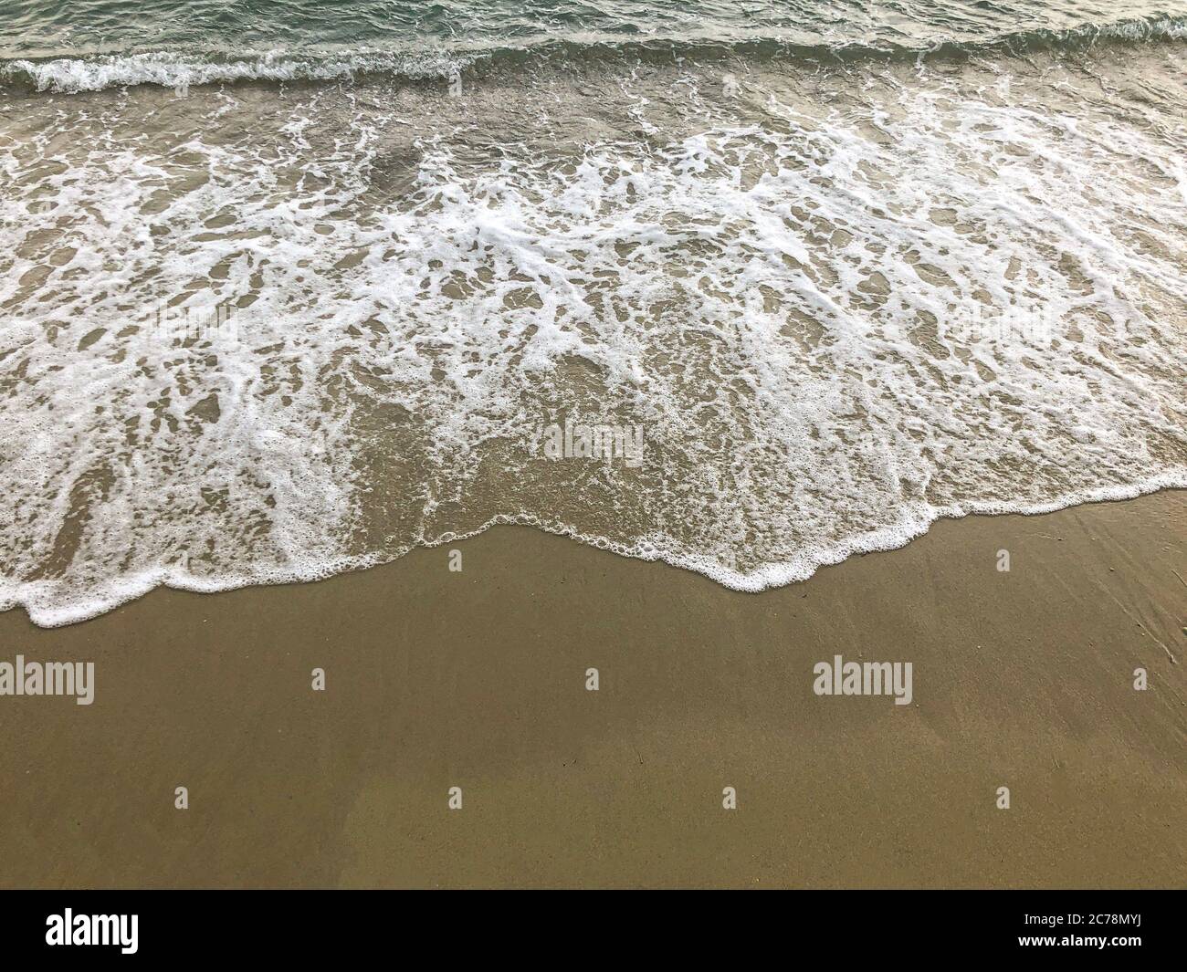 Kleine Wellen am Strand. Wave on Sand Hintergrund, Sommerzeit Stockfoto