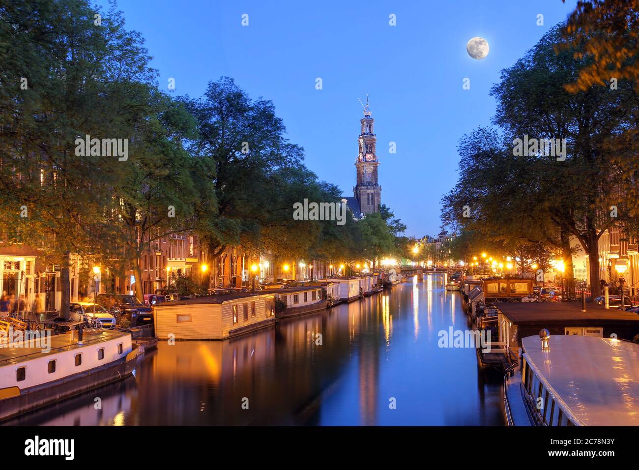 Nachtaufnahme des Prinsengracht-Kanals in Amsterdam (Niederlande) mit dem Turm von Westerkerk und Vollmond. Der überbelichtete Originalmond war repa Stockfoto