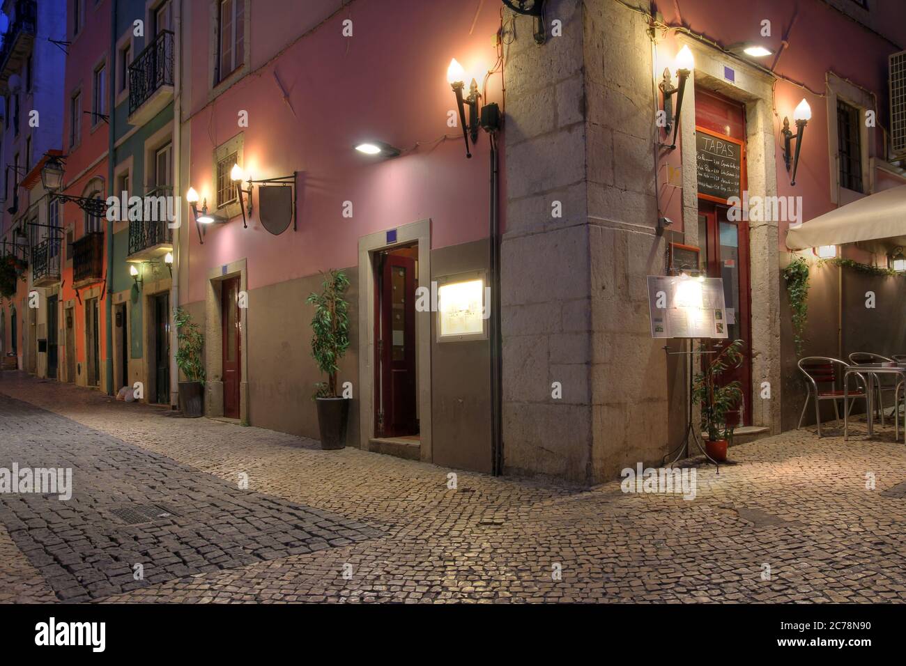 Nachtszene im Viertel Chiado, Lissabon, Portugal, mit einem Tapas-Restaurant in der Ecke. Die engen gepflasterten Straßen und hohen Steingebäude mit Stockfoto