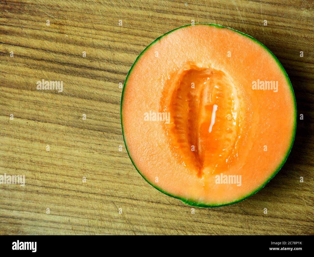 Halbierte Melone mit Melone aus Kantelupe, die auf einem Holzbrett mit Kopierfläche entfernt wurde Stockfoto