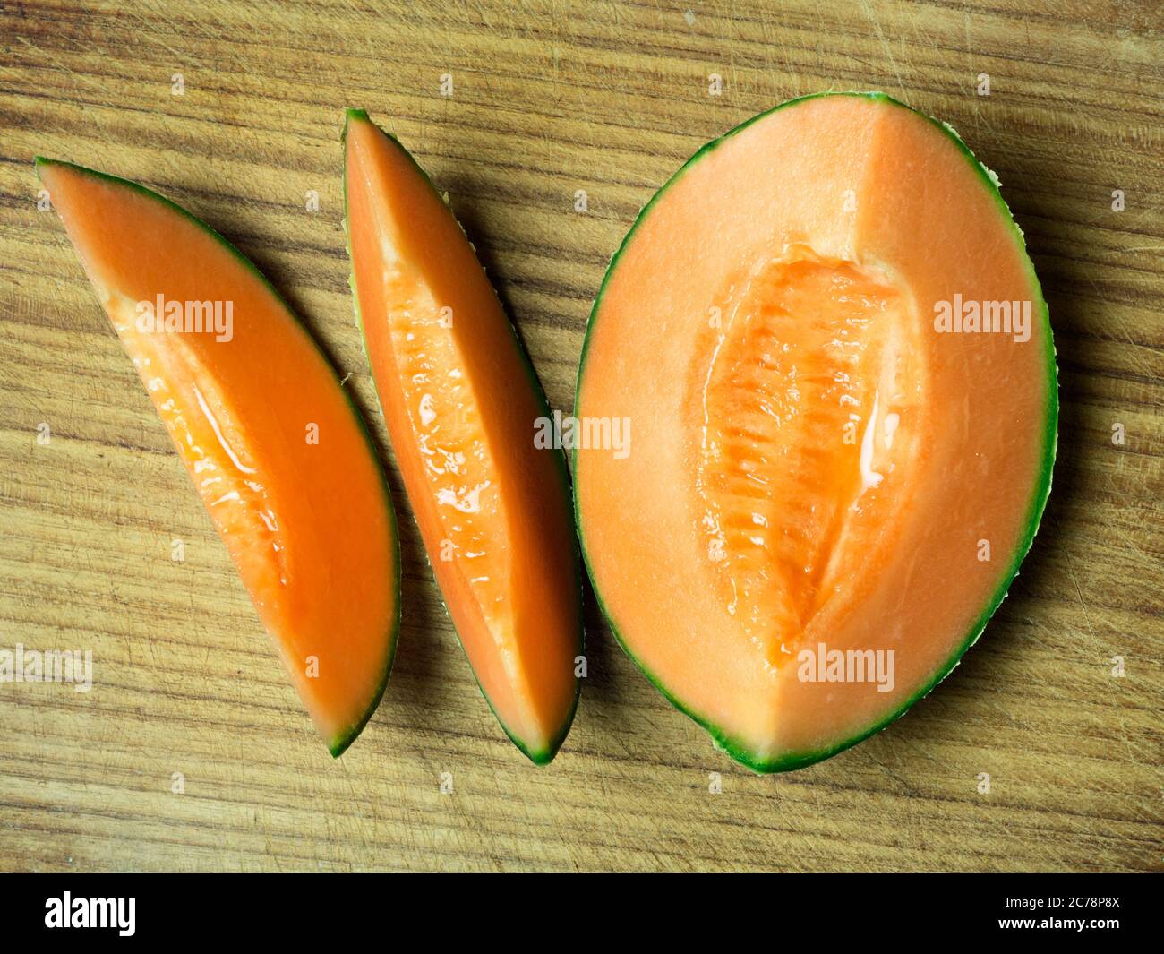 Zwei Melonenscheiben und eine Viertelmelone auf einem Holzbrett Stockfoto