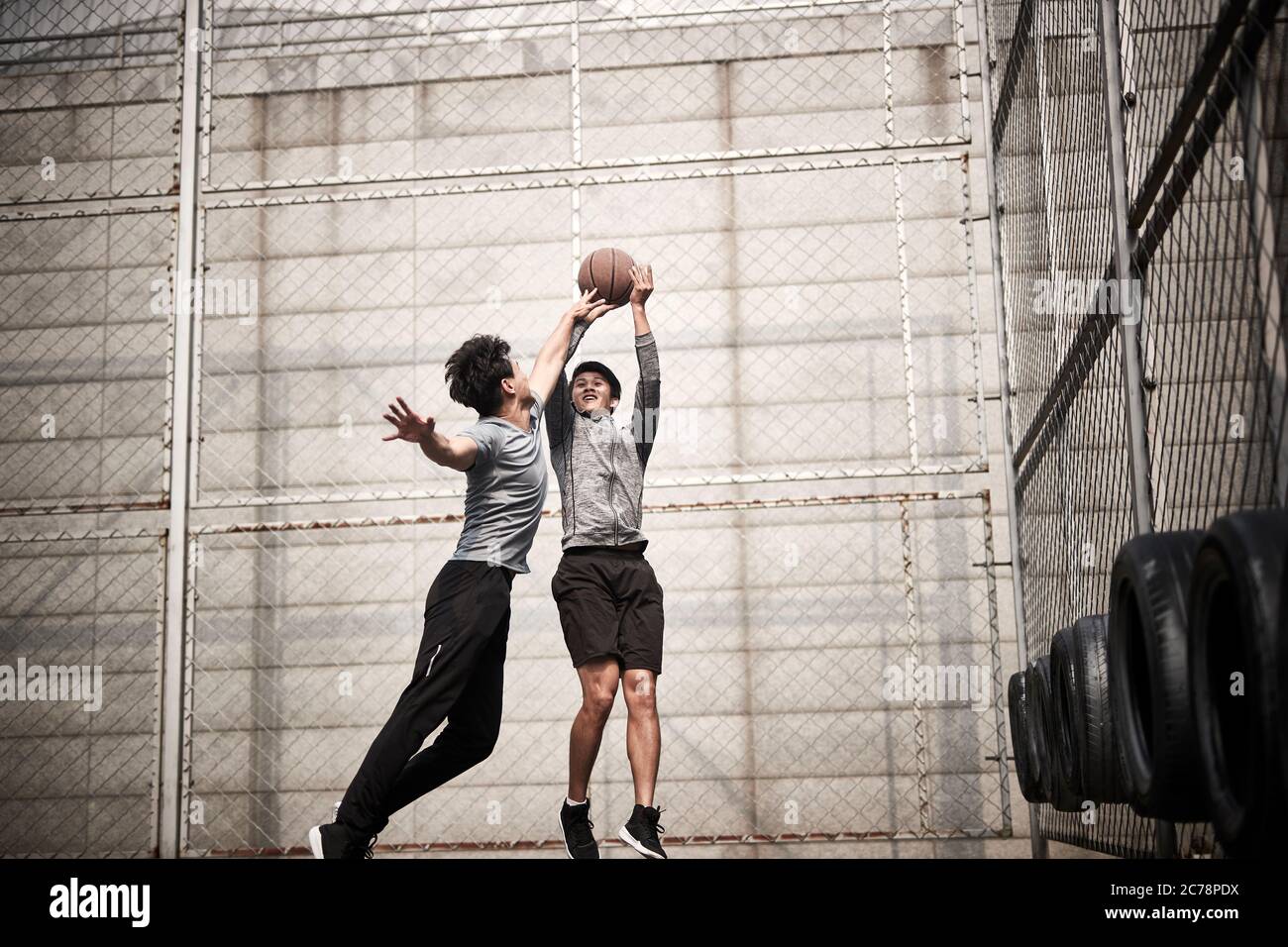 Zwei junge asiatische Erwachsene Männer spielen One-on-One Basketball auf dem Outdoor Court Stockfoto