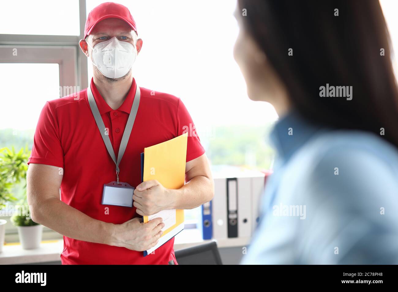 Männlicher Kurier in medizinischer Maske hält Dokumente und lächelt Stockfoto