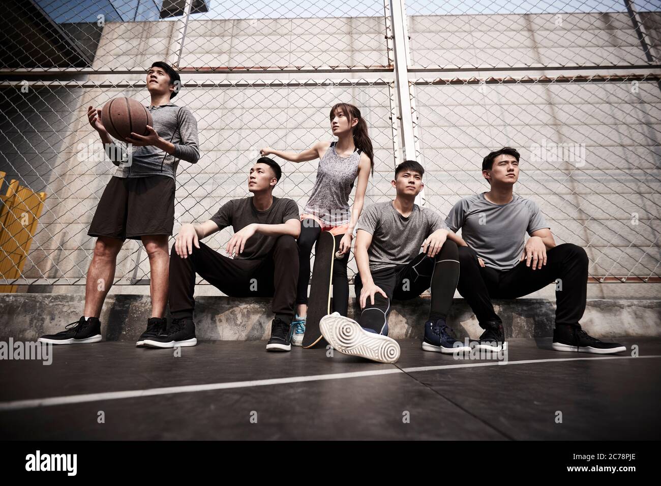 Gruppe von fünf asiatischen jungen Erwachsenen Männer und Frau, die sich auf dem Basketballplatz im Freien entspannen Stockfoto