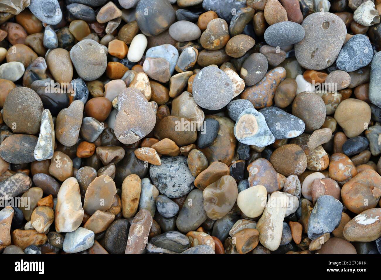 Kieselsteine verschiedener Felsen in verschiedenen Formen, Größen und Farben von einem Strand, der als Hintergrund verwendet werden könnte. Stockfoto