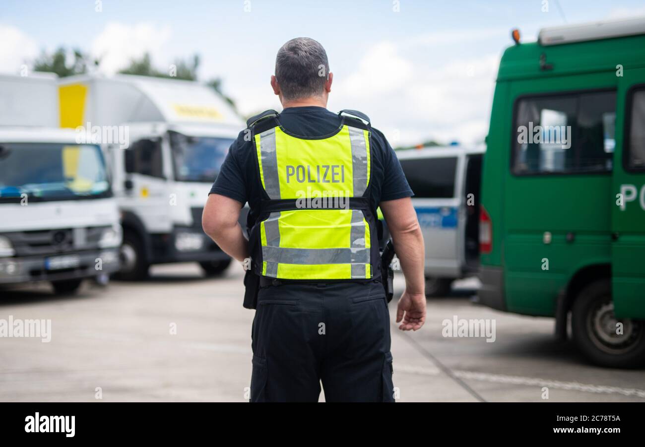 Unna, Deutschland. Juli 2020. Ein Polizist steht zwischen Fahrzeugen auf dem Kolberg-Parkplatz auf der Autobahn 2 in Richtung Hannover. Die Landpolizei Unna führt zusammen mit dem Landesamt für Bildung, Weiterbildung und Personalwesen (LAFP) und Zoll umfangreiche LKW-Kontrollen durch. Der Schwerpunkt der Kontrollen liegt auf der Einhaltung der Sozialvorschriften. Quelle: Jonas Güttler/dpa/Alamy Live News Stockfoto