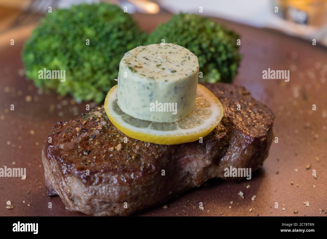 Nahaufnahme eines gerösteten Steak mit Kräuterbutter und Brokkoli auf einem Teller mit Salz und Pfeffer serviert Stockfoto