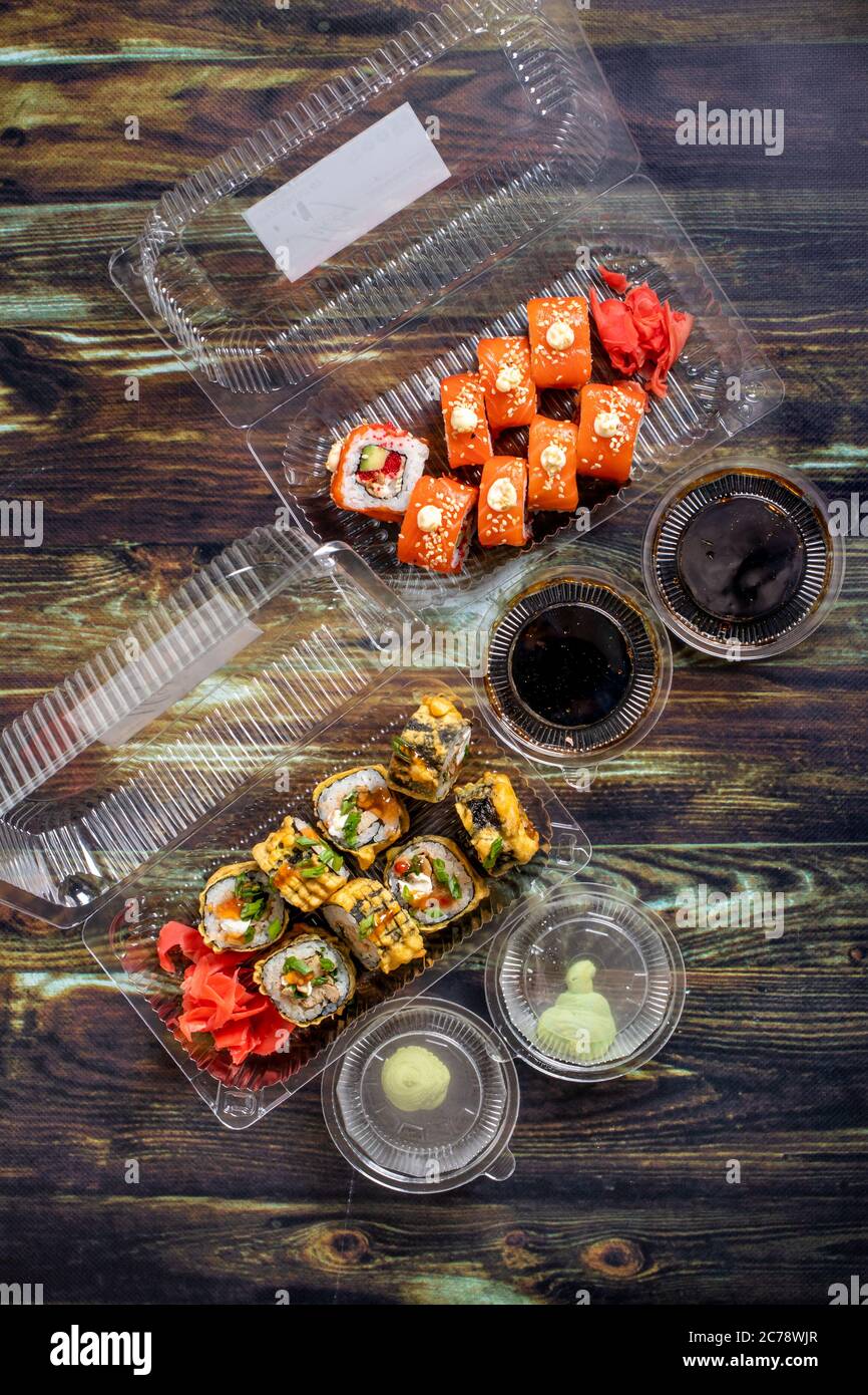 Lebensmittelzustellung nach Hause: Sushi, Brötchen in Einweg-Plastikbehältern. Traditionelle japanische Küche, Meeresfrüchte. Stockfoto