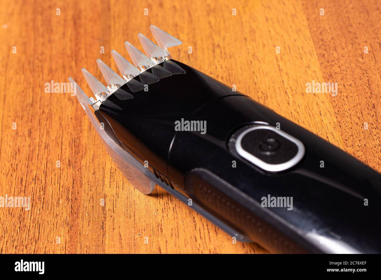 Ein vielseitiger elektrischer Rasiermesser mit Düse zum Modellieren eines Bartes, Schneiden von Haaren und Rasieren auf braunem Holzhintergrund. Stockfoto