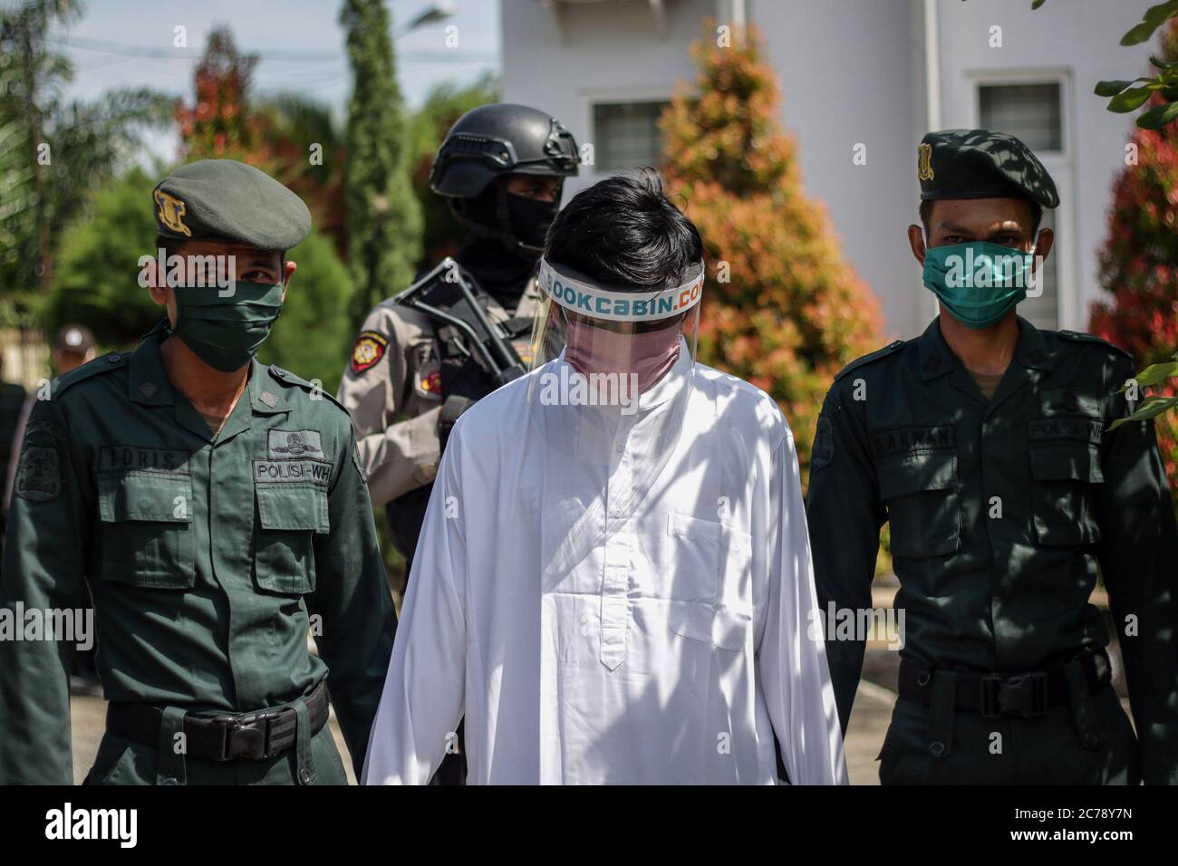 Ein muslimischer Mann, der einen Gesichtsschutz trägt, der von der islamischen Scharia-Polizei begleitet wird und der wegen Verletzung des islamischen Scharia-Gesetzes ausgepeitscht wird, wurde am Mittwoch, dem 15. Juli 2020, als sexuell missbraucht erwiesen, zwei Jungen im Bezirk Nord-Aceh in der Provinz Aceh zu missbrauchen. Ein Mann, der gegen das islamische Gesetz verstößt, wird mit 74 Peitschenhieben bestraft. Aceh ist eine der Provinzen mit der größten muslimischen Mehrheit der Bevölkerung in der Welt, die islamische Scharia Gesetz und Menschen können von verschiedenen Verletzungen, einschließlich Ehebruch, Jarimah, Glücksspiel und Alkohol ausgepeitscht werden. (Foto von Aziz Abdi/INA Photo Agency/Sipa USA) Stockfoto