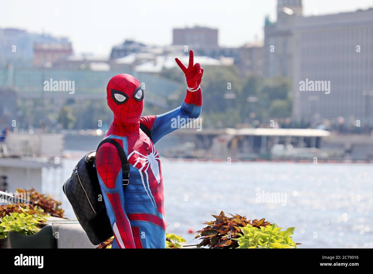 Person im Spider-man Kostüm zeigt das Siegeszeichen am Moskauer Flussufer. Cosplayer in einer Sommerstadt, Unterhaltung und Hobby Stockfoto