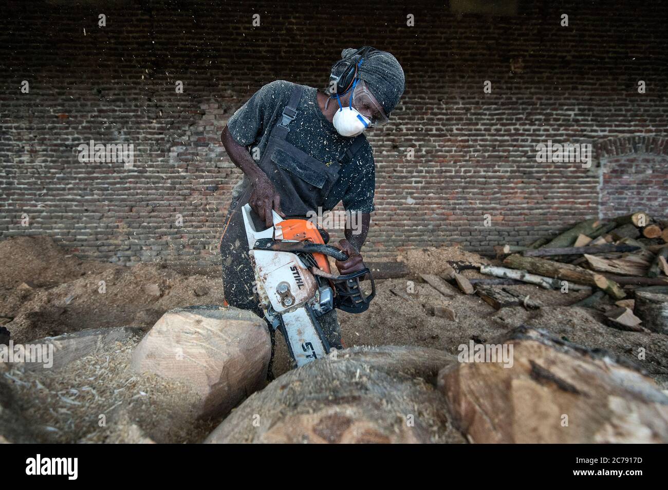Der ivorische Bildhauer Jems Robert Koko Bi bearbeitet einen Baumstamm mit der Motorsäge. Stockfoto