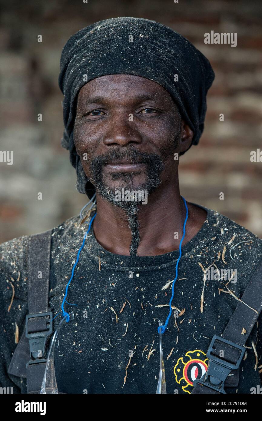 Der ivorische Bildhauer Jems Robert Koko Bi bearbeitet einen Baumstamm mit der Motorsäge. Stockfoto