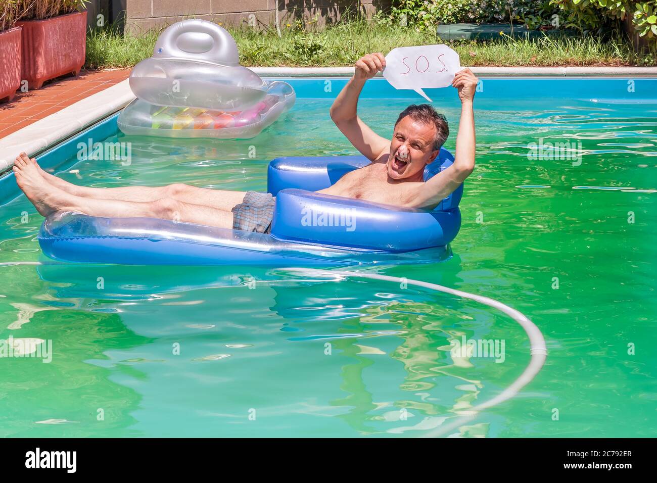Ein weißer Mann auf einer aufblasbaren Matratze in einem Schwimmbad hält die S.O.S. um Hilfe zu bitten Stockfoto