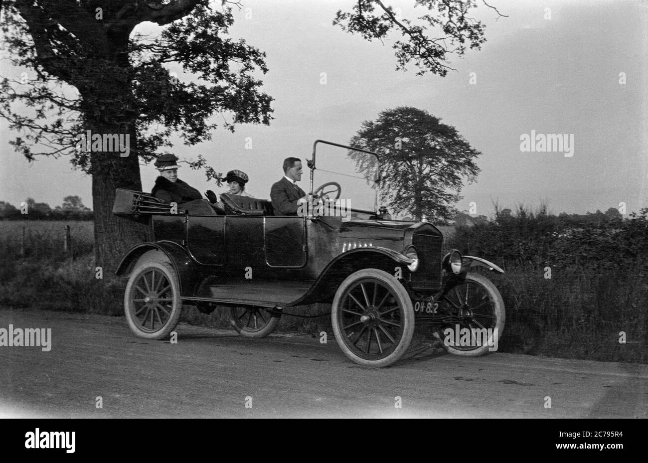 Ein edwardianisches Foto des frühen 20. Jahrhunderts, aufgenommen in England, zeigt einen Ford Model T mit zwei Damen im Rücken, die von einem Mann angetrieben werden. Stockfoto