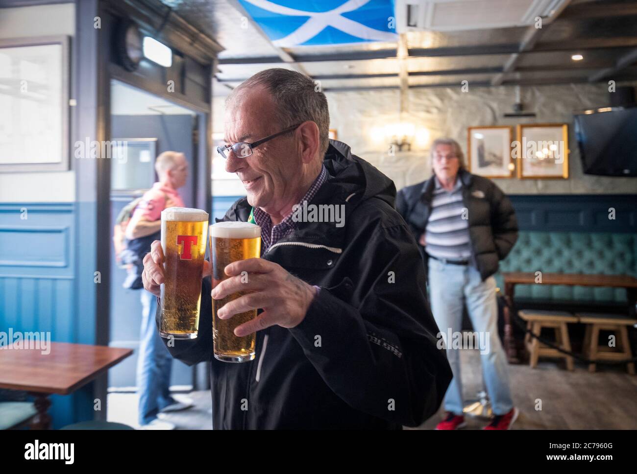 George McDonald von Clemiston ist der erste Kunde, der im Scotsman's Lounge Pub in Edinburgh serviert wird, da Pubs, Bars und Restaurants in ganz Schottland zum ersten Mal seit März nach Aufhebung der weiteren Beschränkungen für die Sperrung durch Coronaviren Innenbereiche eröffnet haben. Stockfoto