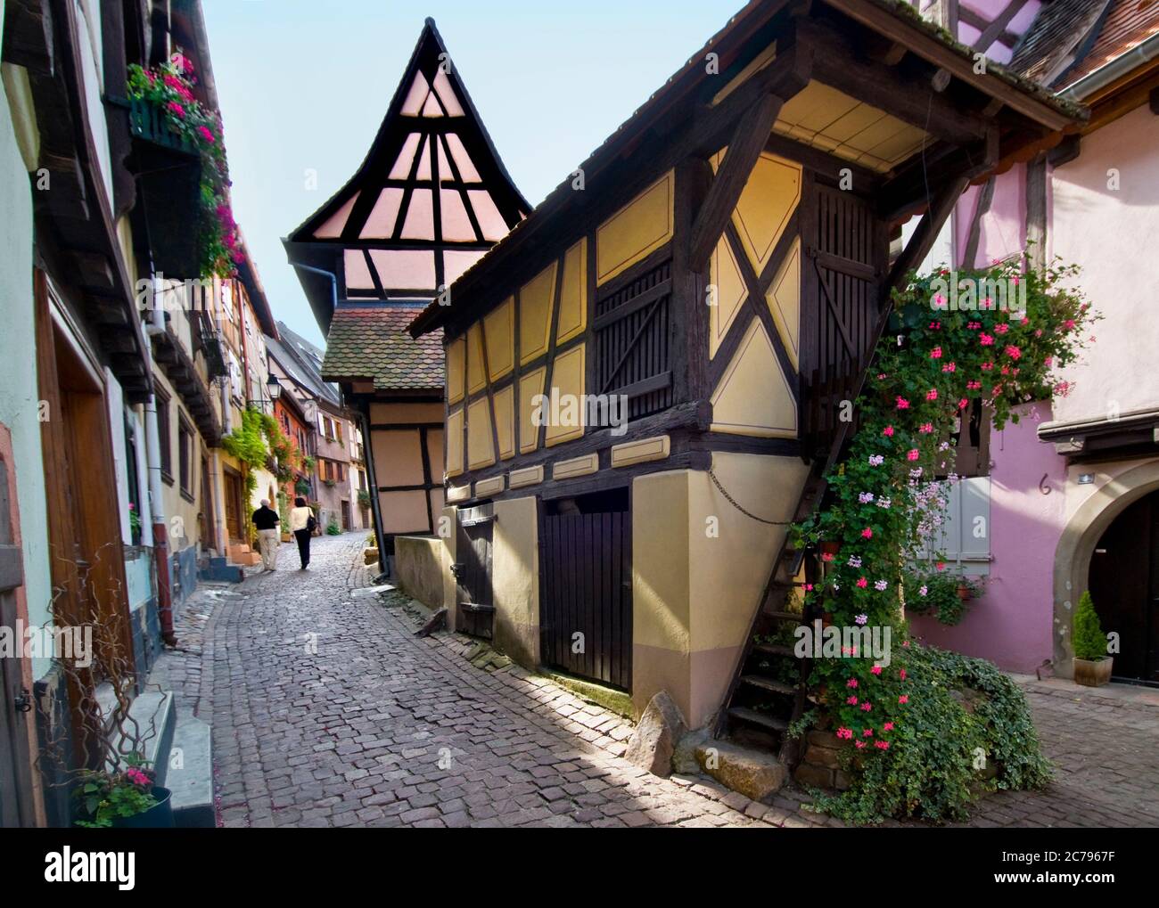 EGUISHEIM Rue du Rempart Eguisheim mittelalterliches Weindorf mit Touristen Paar zu Fuß die historische gepflasterte Straße Eguisheim Elsass Frankreich Stockfoto