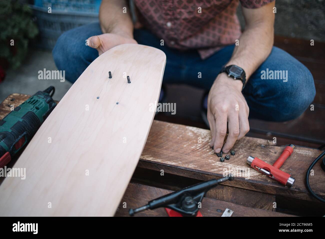 Skateboard Deck aus Holz mit Bolzen in den Händen des Mannes Stockfoto