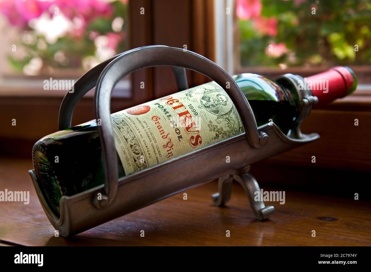 Chateau Petrus Pomerol 1999 feiner roter Bordeaux-Wein, offene Flasche belüftet am Tisch in Vintage-Metall-Ausgiessmaschine Flaschenwiege im luxuriösen floralen Restaurant Speisesaal Stockfoto