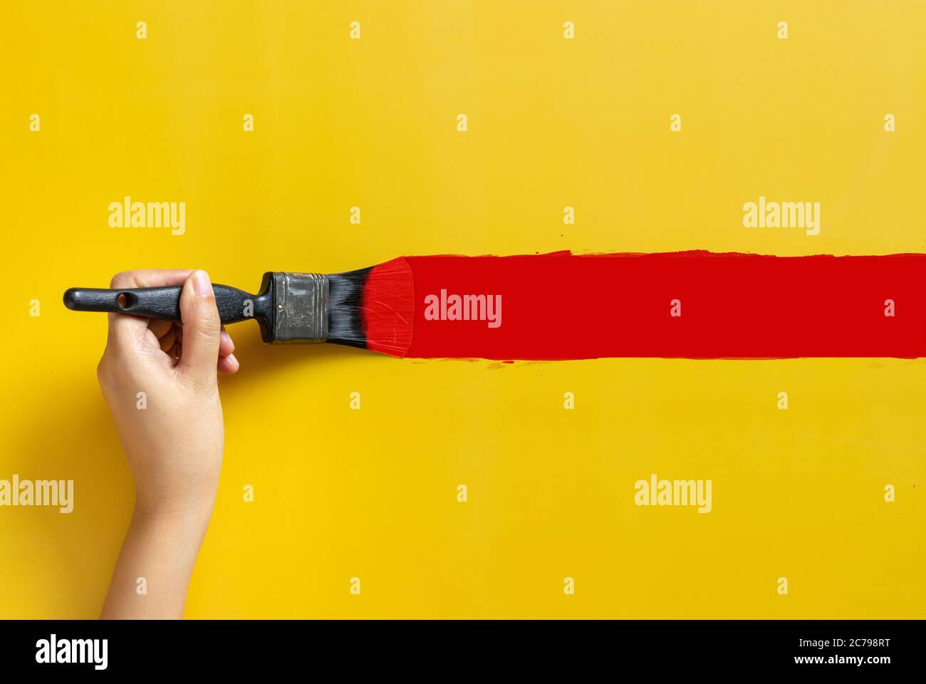 Hand halten Pinsel, rot lackiert Farbe isoliert auf gelbem Hintergrund mit Kopierer Raum. Home Verbesserung Konzept Stockfoto
