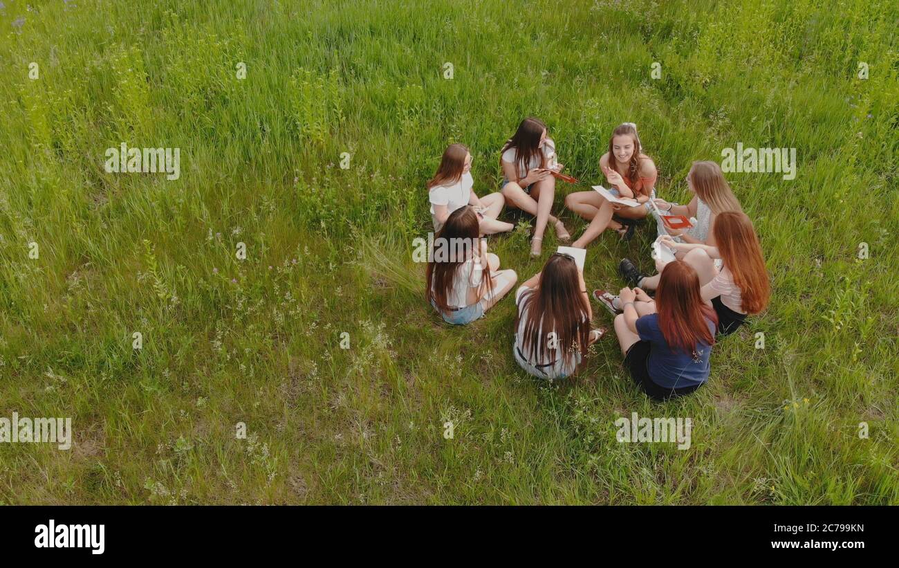 Teamwork-Konzept. Eine Gruppe Studentinnen sitzt auf dem Gras und löst Probleme. Stockfoto