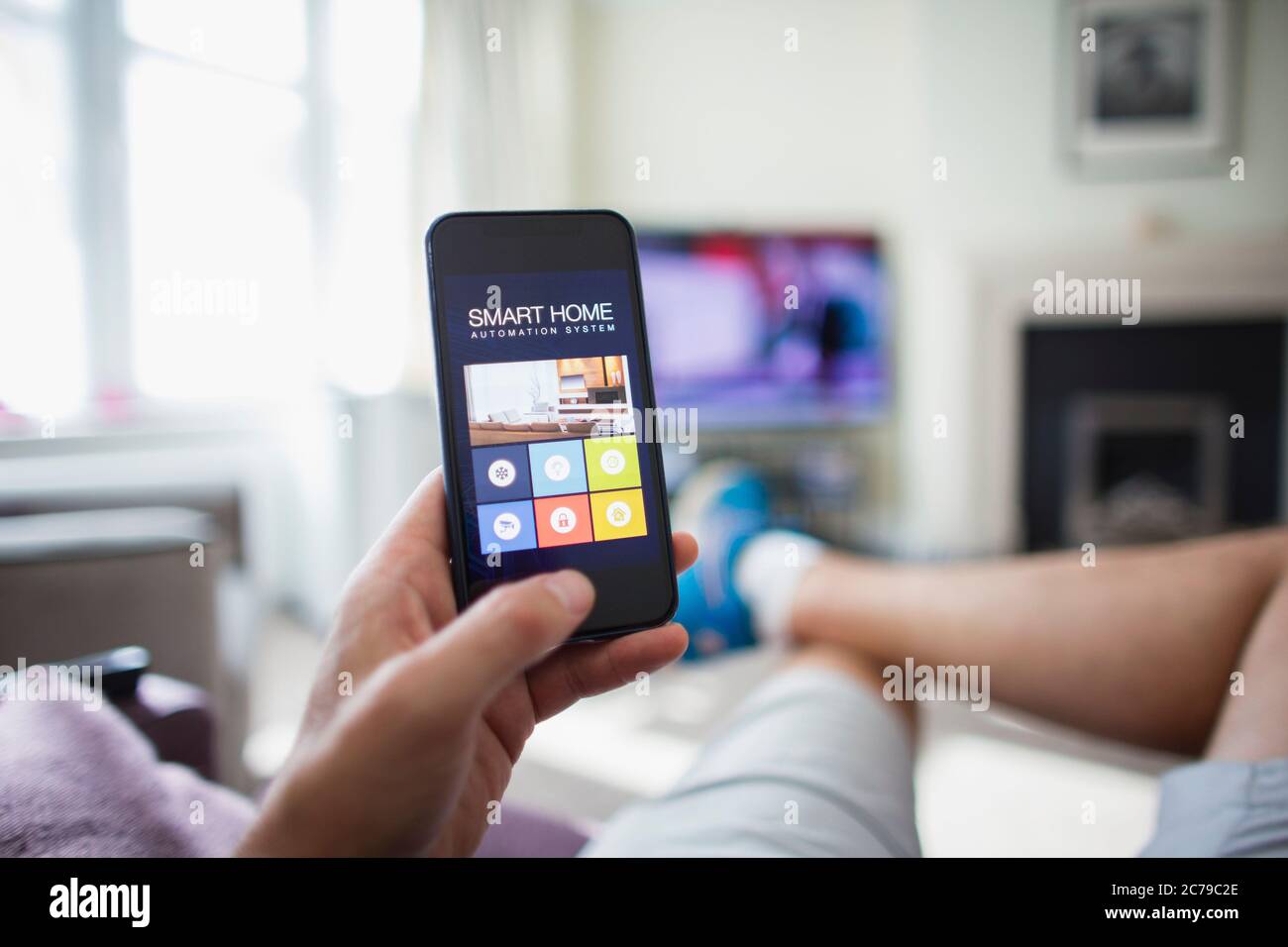 POV Mann Überprüfung Home Automation auf Smartphone im Wohnzimmer Stockfoto