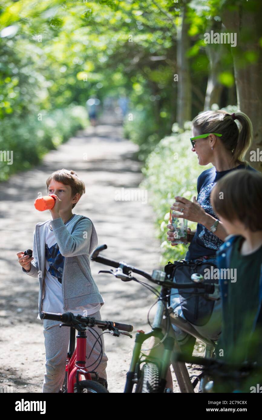Mutter und Söhne trinken Wasser auf der Fahrradtour Stockfoto