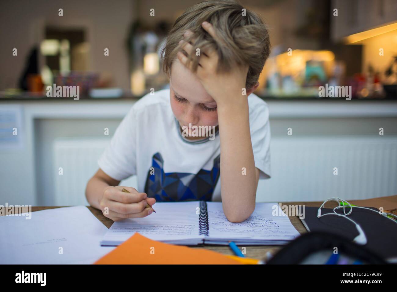 Fokussierter Junge, der Hausaufgaben am Tisch macht Stockfoto