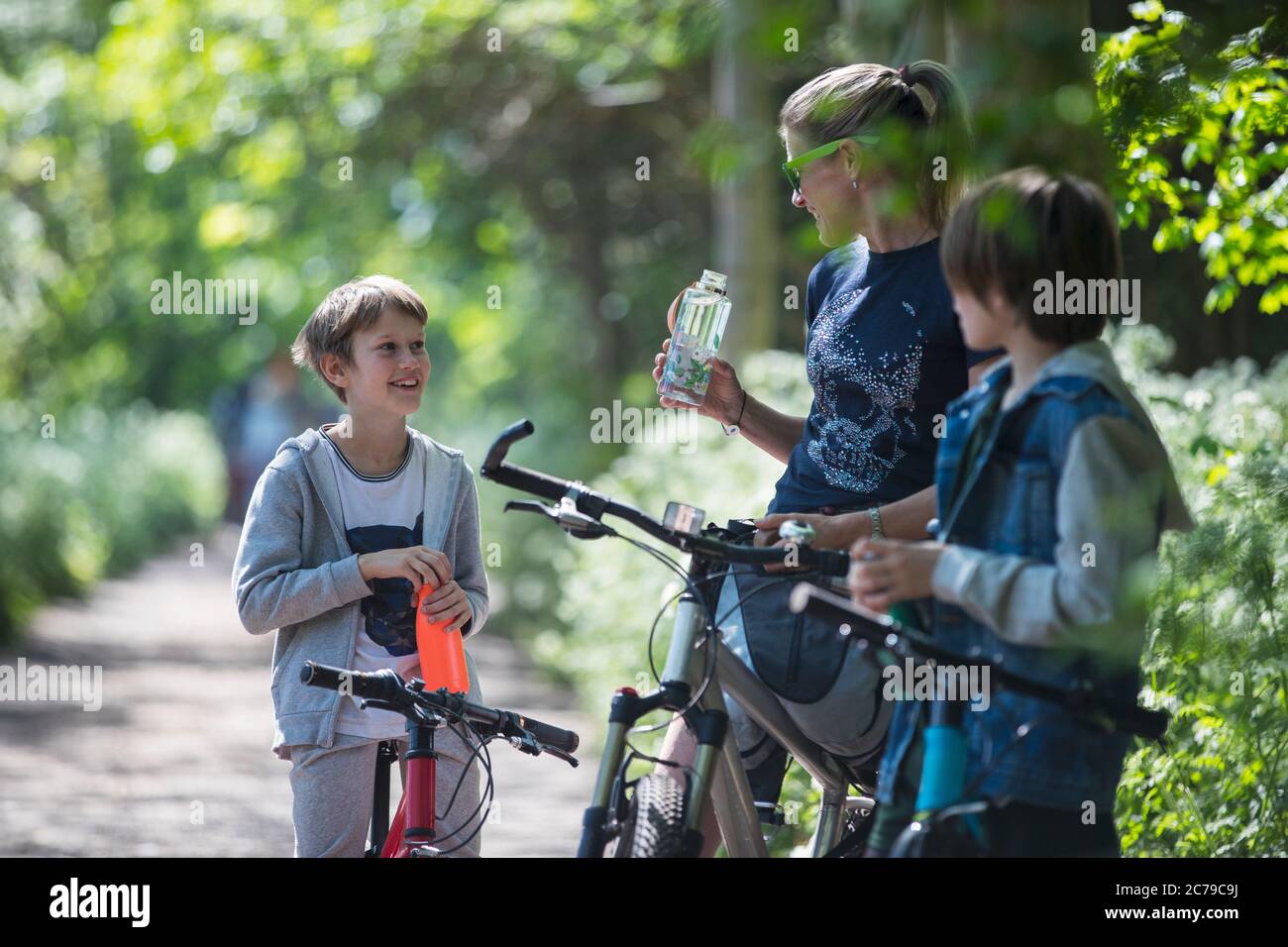 Mutter und Söhne trinken Wasser auf der Fahrradtour Stockfoto