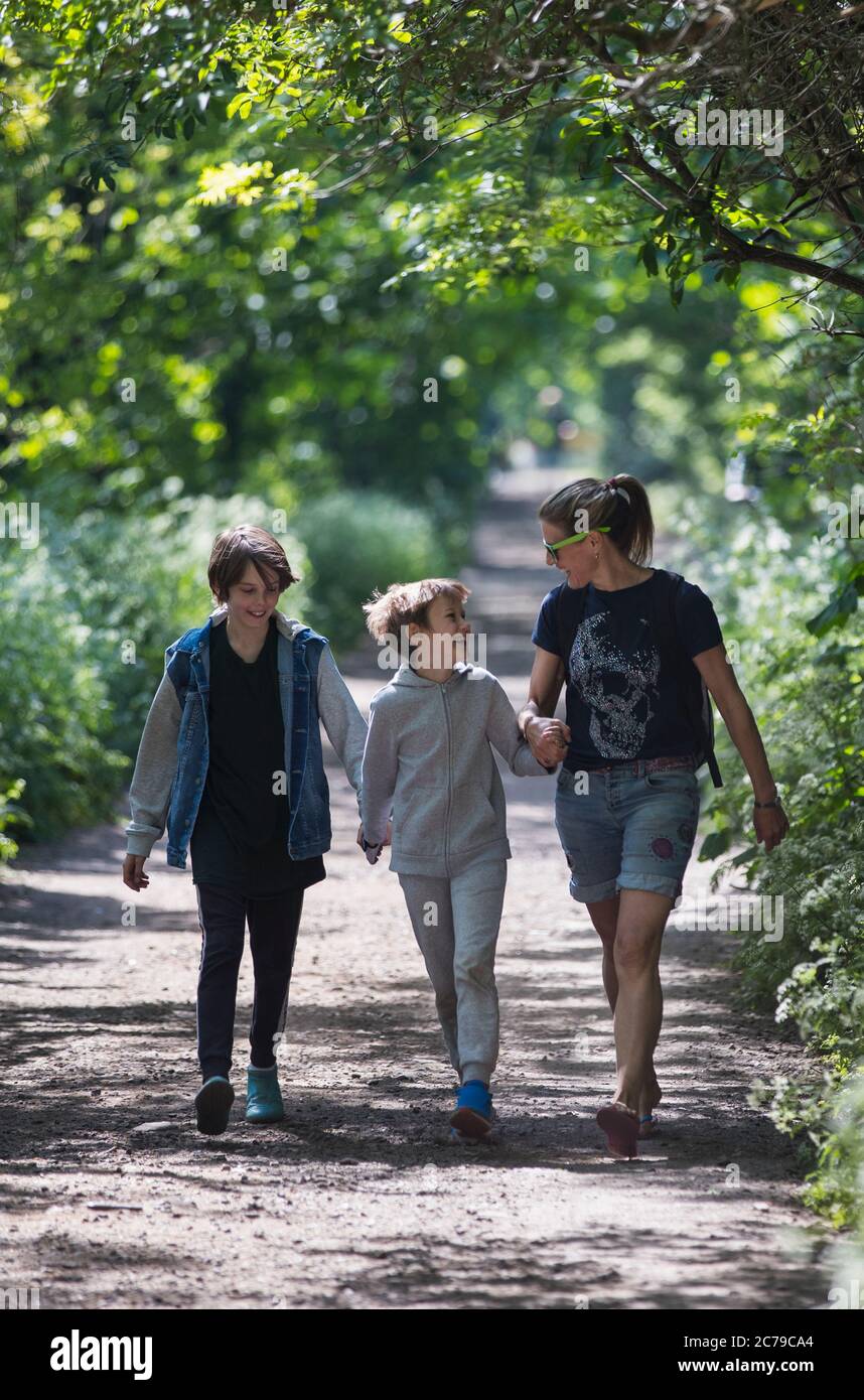 Mutter und Söhne gehen auf sonnigem Parkweg Stockfoto